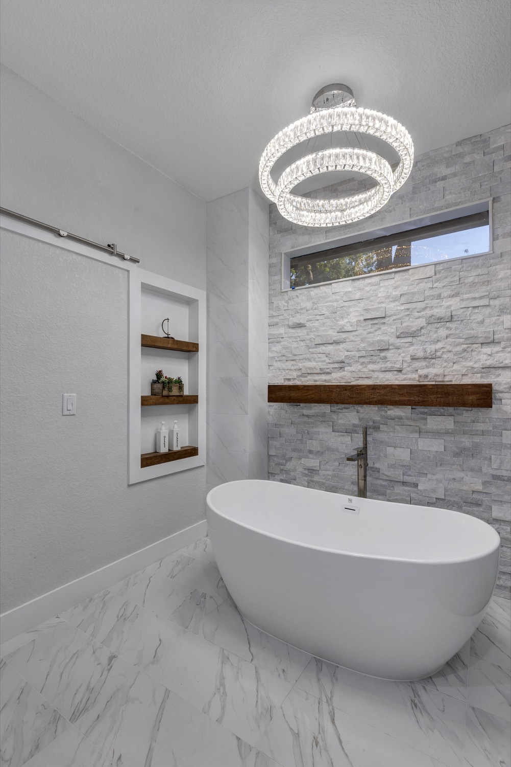 Bathroom renovation featuring a white freestanding tub and chandelier by Talbot Custom Homes in Orlando, FL